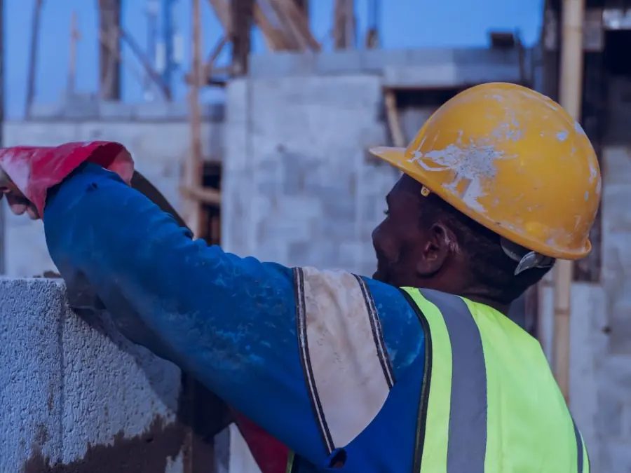 Maçon en gilet de sécurité montant un mur en blocs béton