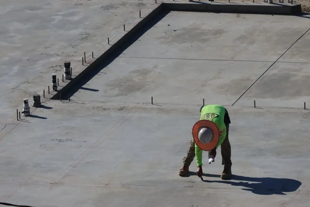 Ouvrier lissant une grande dalle de béton