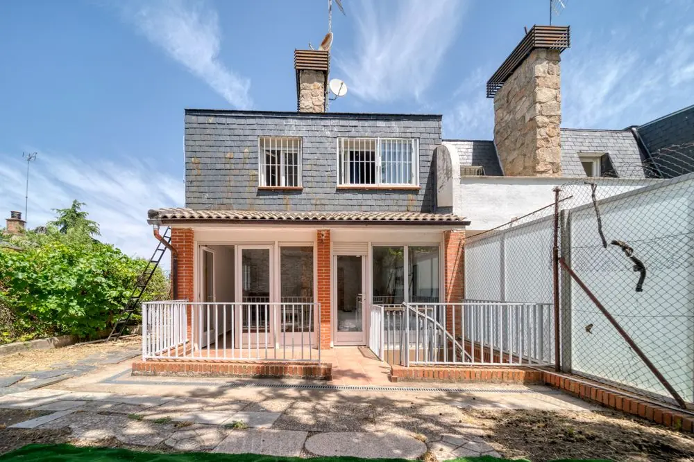 Maison en brique avec clôture blanche et allée en béton
